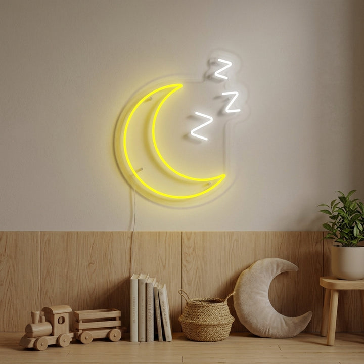 Sleepy Moon with ZZZ neon sign glowing softly on a wall in a decorated kids' room, above a bed with plush toys and bedding.