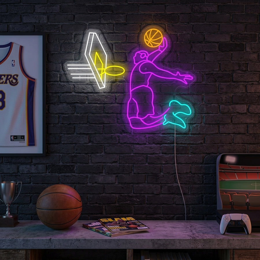 A lifestyle photo showing the illuminated 'Basketball James Dunk' neon sign mounted on a bedroom wall above a desk, adding a dynamic glow to the sports-themed decor.