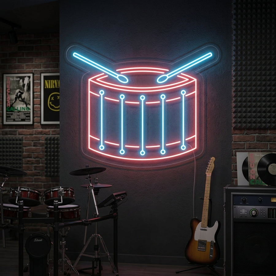 A glowing red and blue Drum Neon Sign mounted on a brick wall above a drum kit in a music room setting.