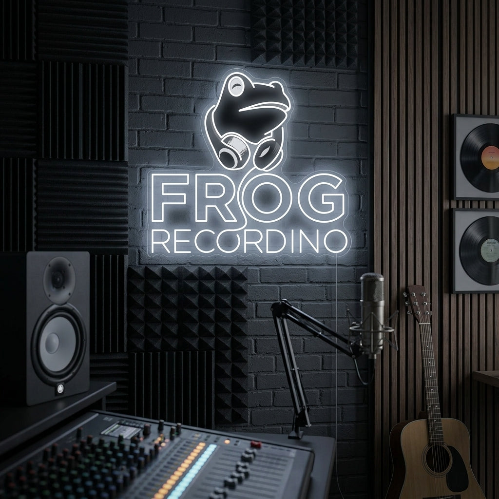 A illuminated neon sign showing a cartoon frog wearing headphones and using a mixing desk, with glowing text above reading 'FROG RECORDING', mounted on an exposed brick wall.