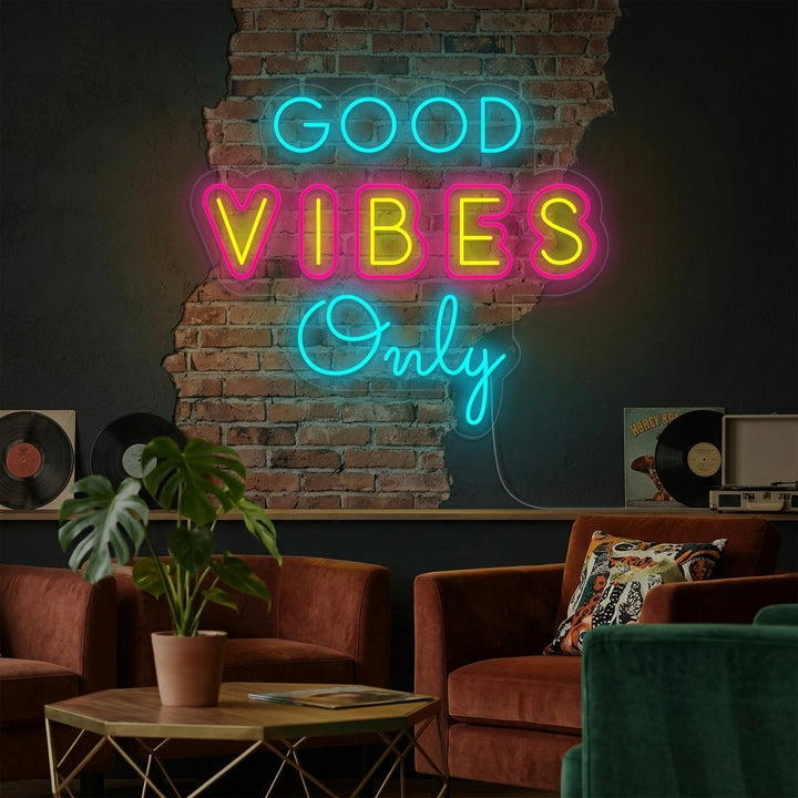 Lifestyle image of the Unique Good Vibes Only Neon Sign glowing in a cozy bedroom setting, above a decorated nightstand.