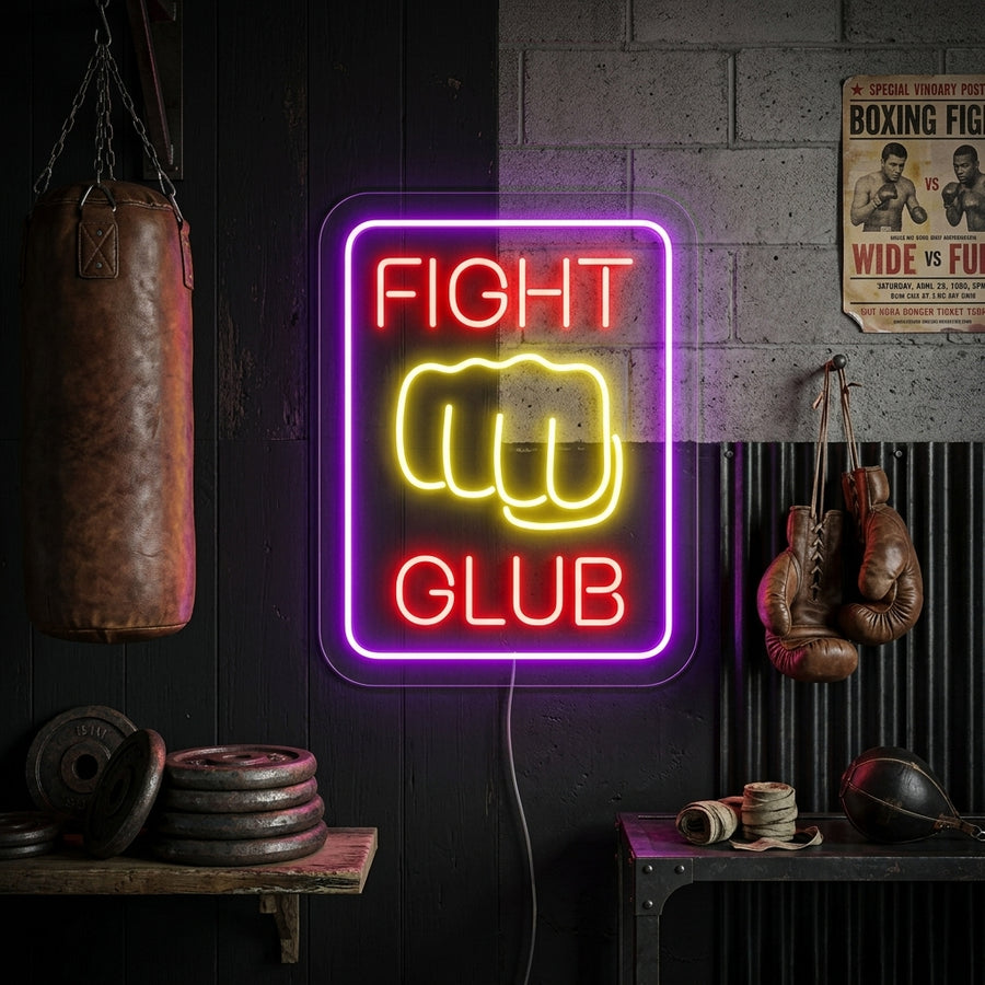 A candid lifestyle photo of the 'Fighting Club' neon sign with boxing glove graphic illuminating a cozy urban apartment or studio at night, mounted above a leather chair.