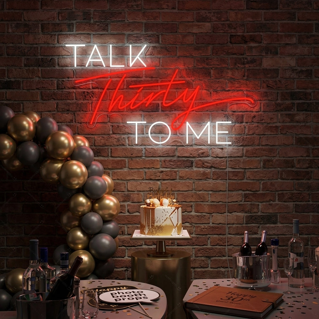 A lifestyle shot showing the 'Talk Thirty To Me' neon sign mounted on a wall above a couch in a modern living room setting.