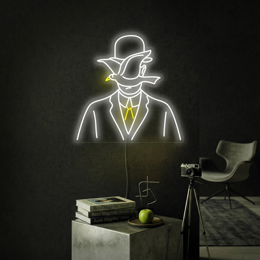 A lifestyle shot showing the Rene Magritte 'Man in A Bowler Hat' neon sign glowing on a textured office wall.