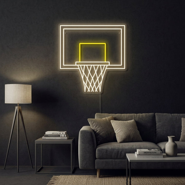 A glowing blue neon sign depicting a basketball hoop and net with an orange neon basketball passing through, mounted on a rustic wood plank wall in a cozy room setting.