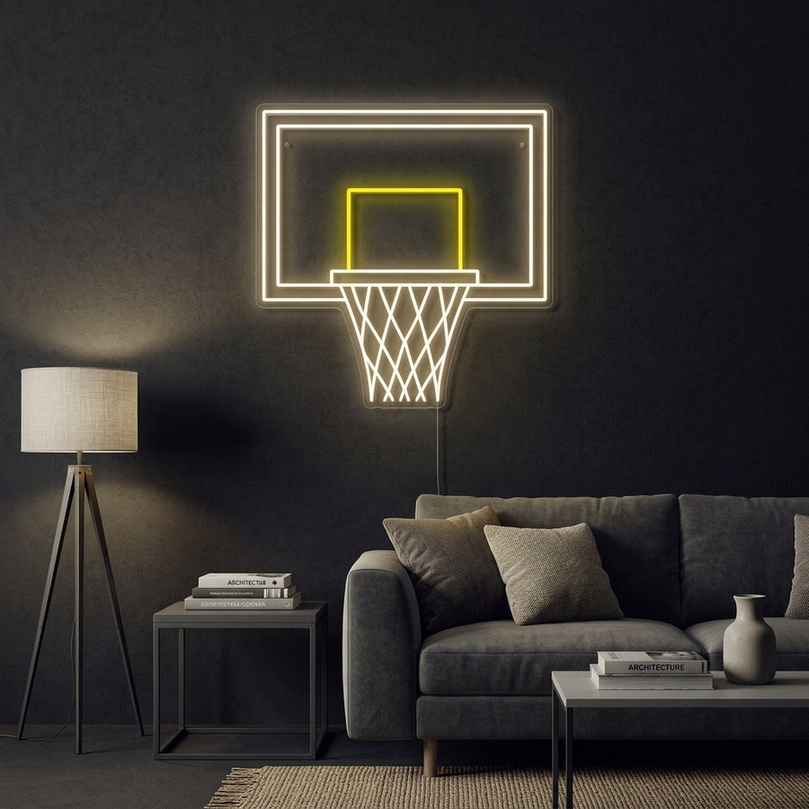 A glowing blue neon sign depicting a basketball hoop and net with an orange neon basketball passing through, mounted on a rustic wood plank wall in a cozy room setting.
