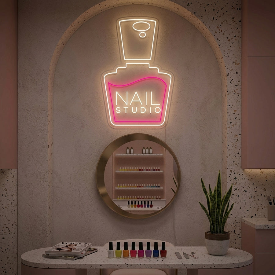 A bright, stylized 'Nails Studio' neon sign glowing on a textured wall within a modern, aesthetically pleasing nail salon interior.