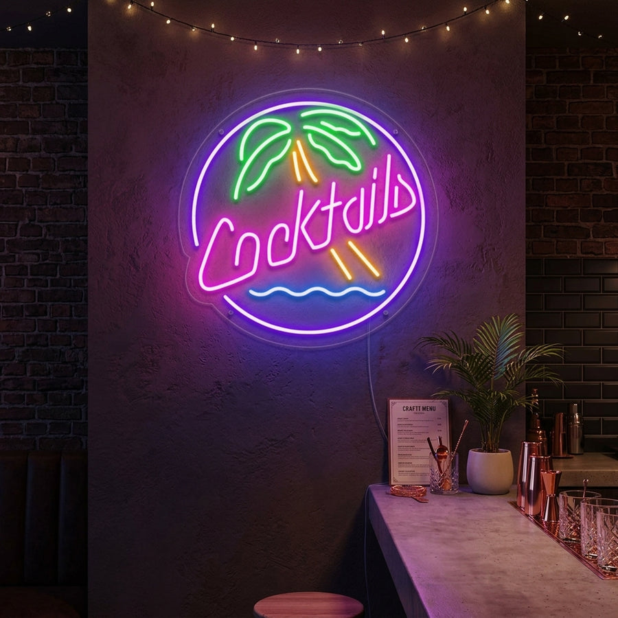 A vibrant 'Cocktails' neon sign glowing in bright pink script with a blue underline, mounted on a rustic wooden plank wall in a home bar setting.