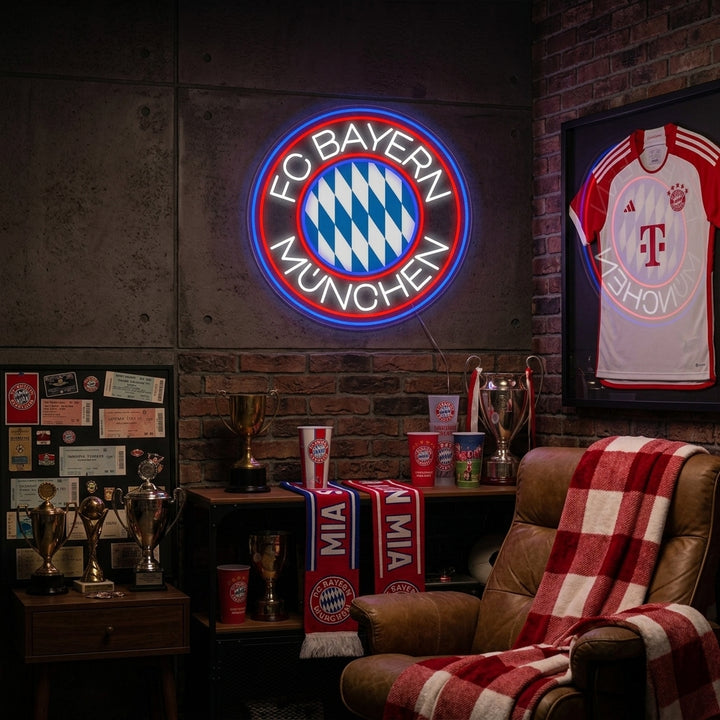 FCBM Football neon sign glowing on a textured brick wall in a cozy fan cave environment.