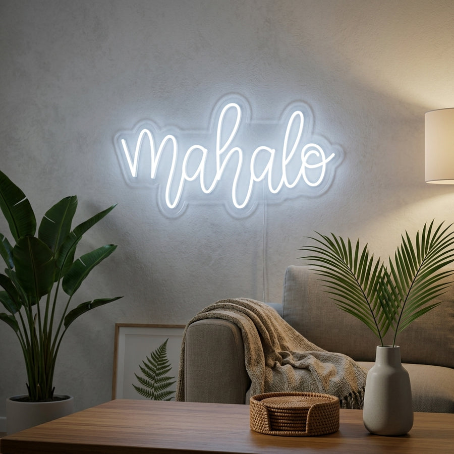 A glowing 'Mahalo' neon sign with Hawaiian thank you text, displayed as wall decor in a modern living room setting.