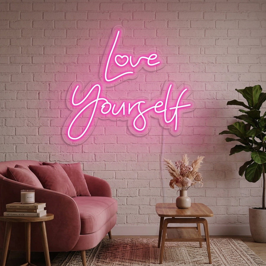 A lifestyle photo of the 'Love Yourself' neon sign glowing beautifully above a stylized bedside setup in a cozy, modern bedroom.