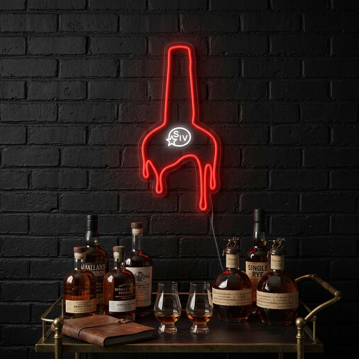 A Maker's Whiskey neon sign illuminating a bar area.