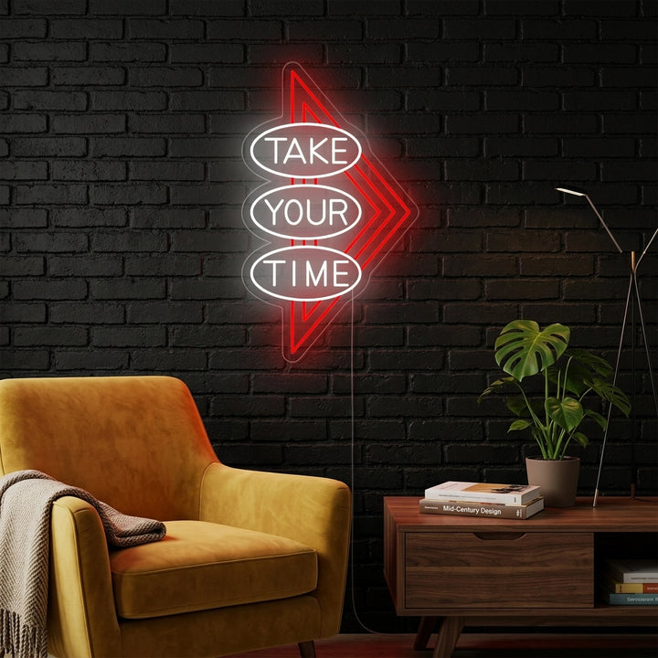 A candid lifestyle photo of the 'Take Your Time' neon sign glowing above a modern desk in a home office.