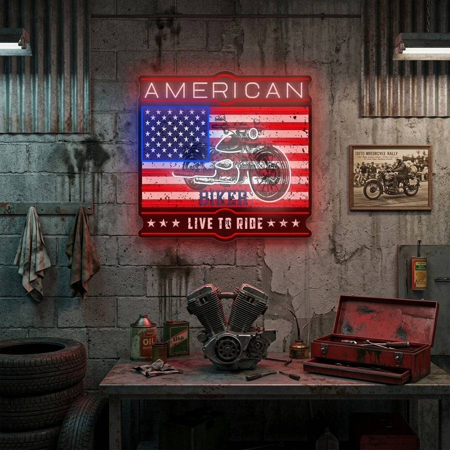 A illuminated American Biker Live To Ride neon sign hanging on a dark wall, showing bright white and amber light.