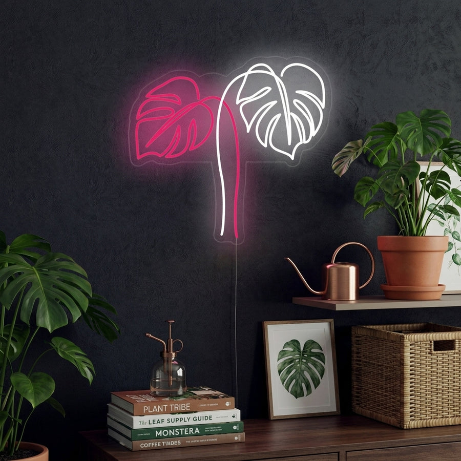 A glowing Monstera Leaves neon sign mounted on a textured wall in a modern living room setting.