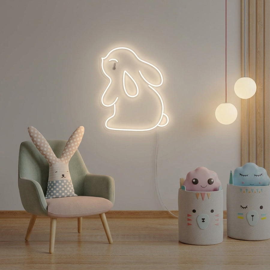 A cozy nursery featuring a glowing Rabbit Bunny neon sign mounted on the wall above a crib, casting a warm light.