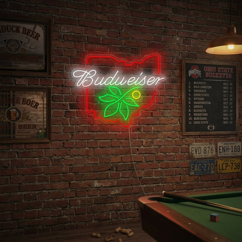A lifestyle photograph of the BUD OHIO BUCKEYE neon sign glowing vibrantly on the brick wall of a lively bar, with wooden furniture and other patrons in the blurred background.