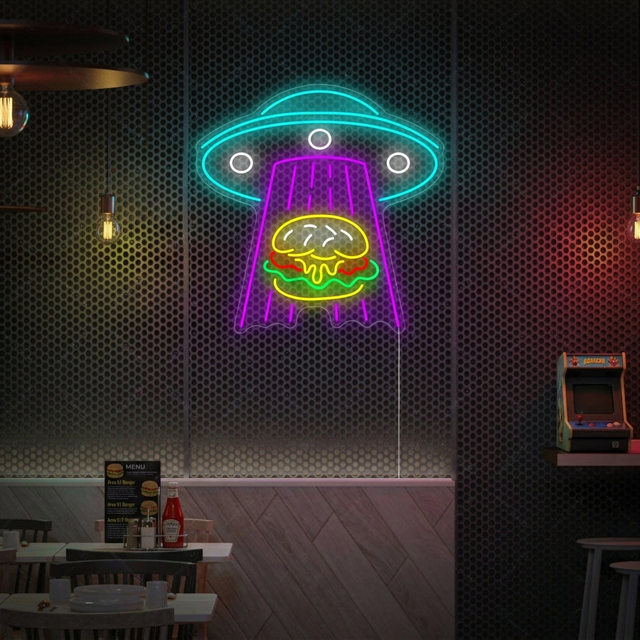 A lifestyle photo showing the 'UFO Kidnapping Burger' neon sign glowing brightly on a brick wall above a sofa.