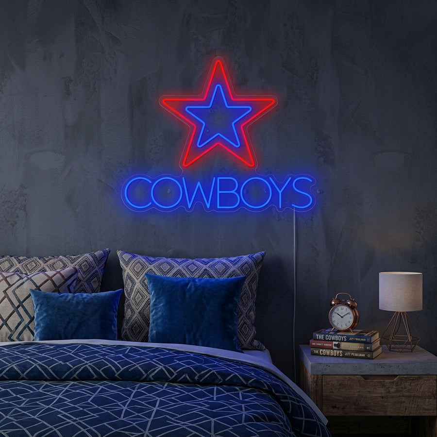 Handcrafted glowing blue Cowboys neon sign mounted on a textured brick wall in a cozy home bar setting.