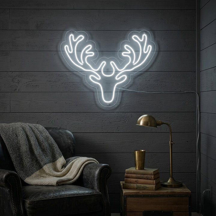 A glowing deer neon sign illuminates a contemporary living room above a sofa, casting a warm light against the wall.