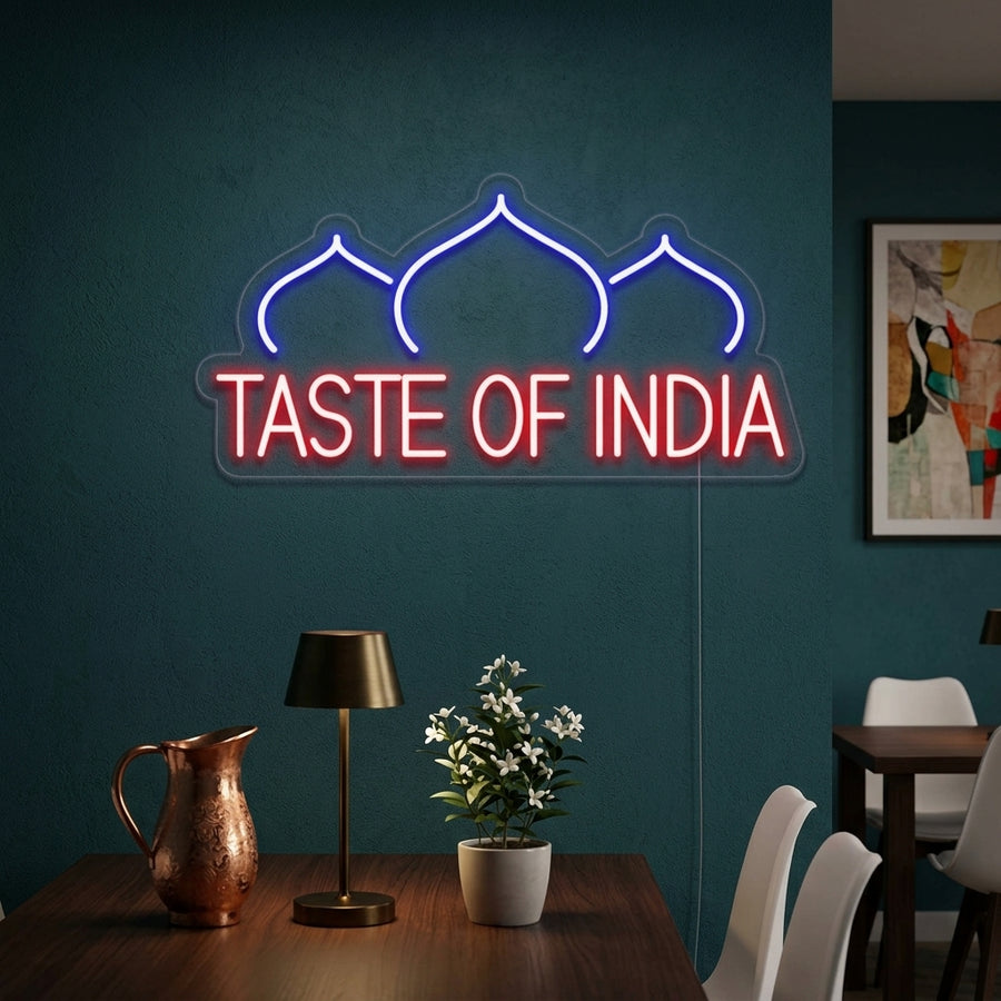 A lifestyle photo showing the TASTE OF INDIA RESTAURANT neon sign glowing warmly on a restaurant wall, enhancing the dining atmosphere.