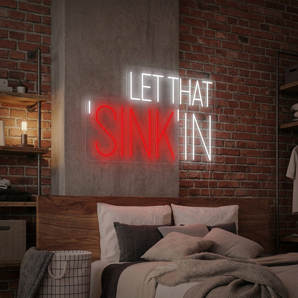 A glowing 'Let That Sink In' neon sign in white and pink scripts, mounted above a minimalist white bathroom sink and vanity with modern fixtures.