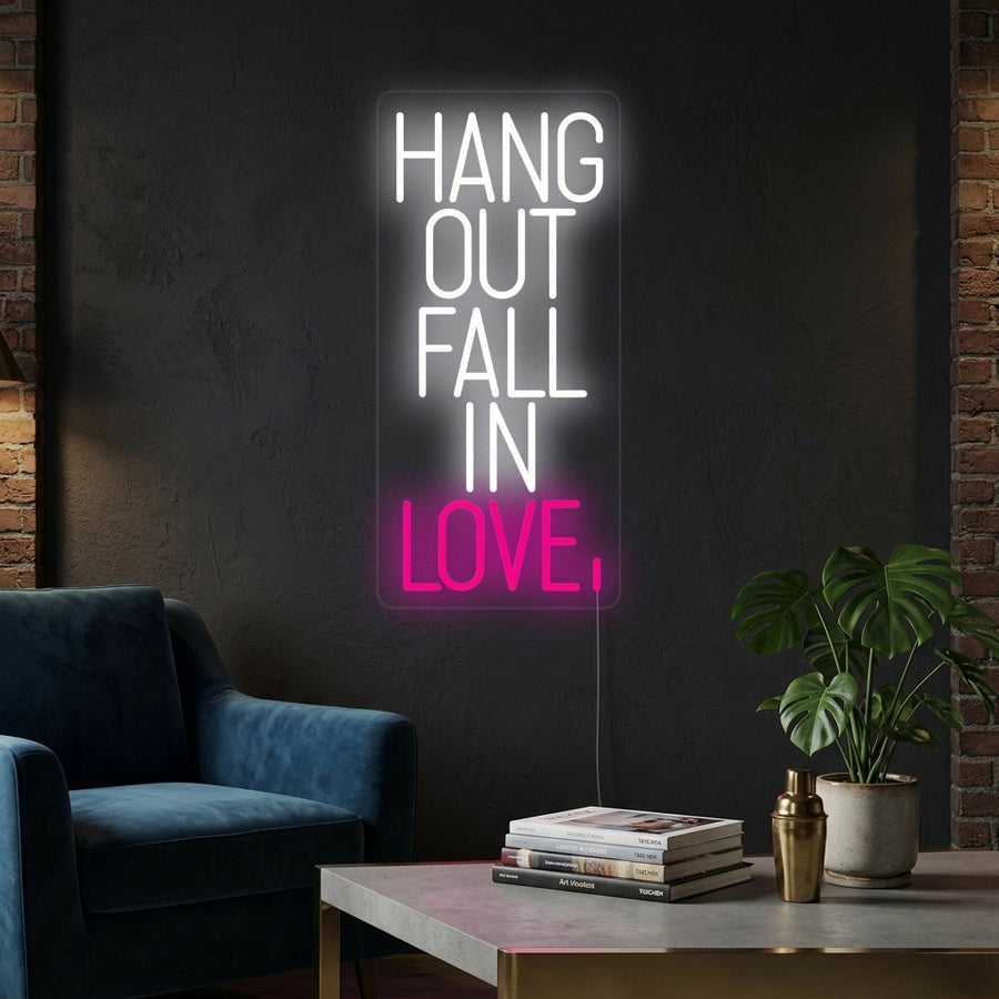 A glowing 'Hang Out Fall In Love' neon sign in a contemporary living room setting.