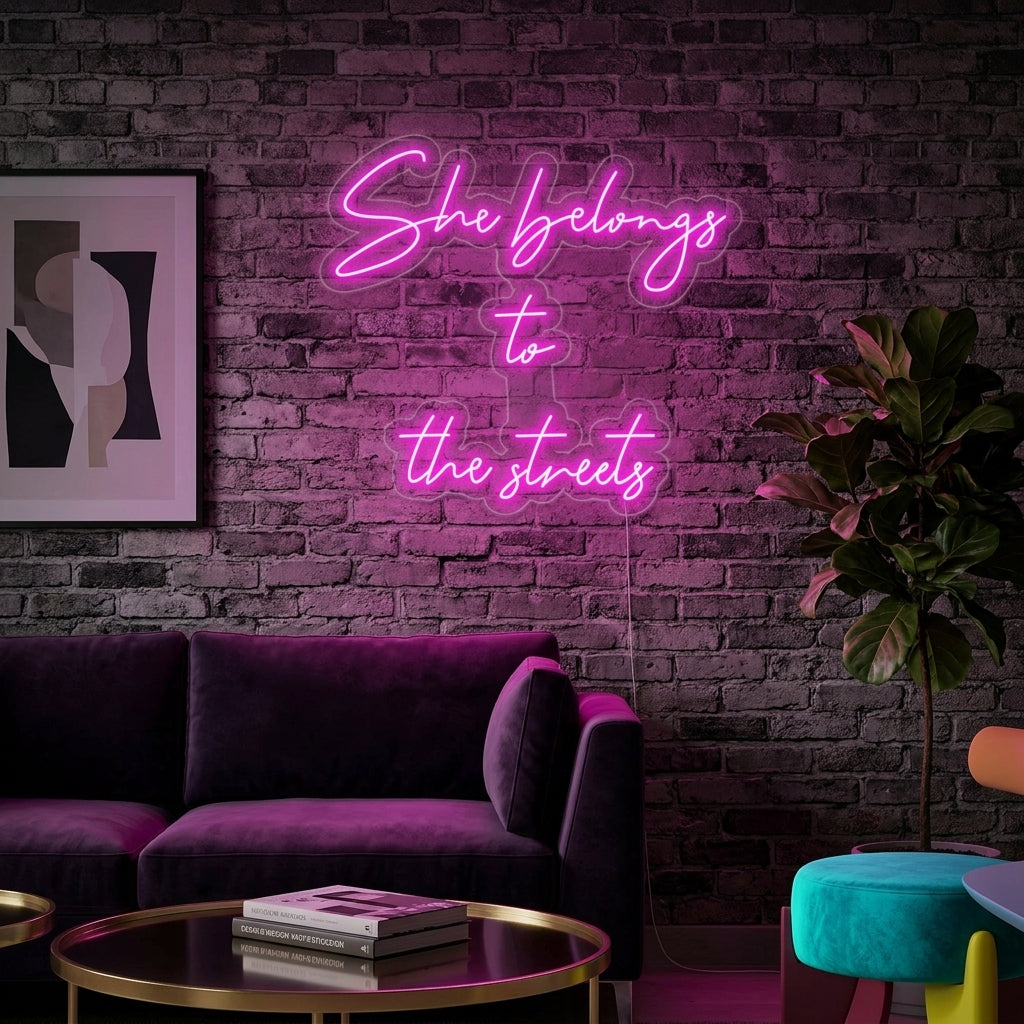 White glowing text 'She Belongs To The Streets' neon sign on a charcoal grey brick wall in a modern living room
