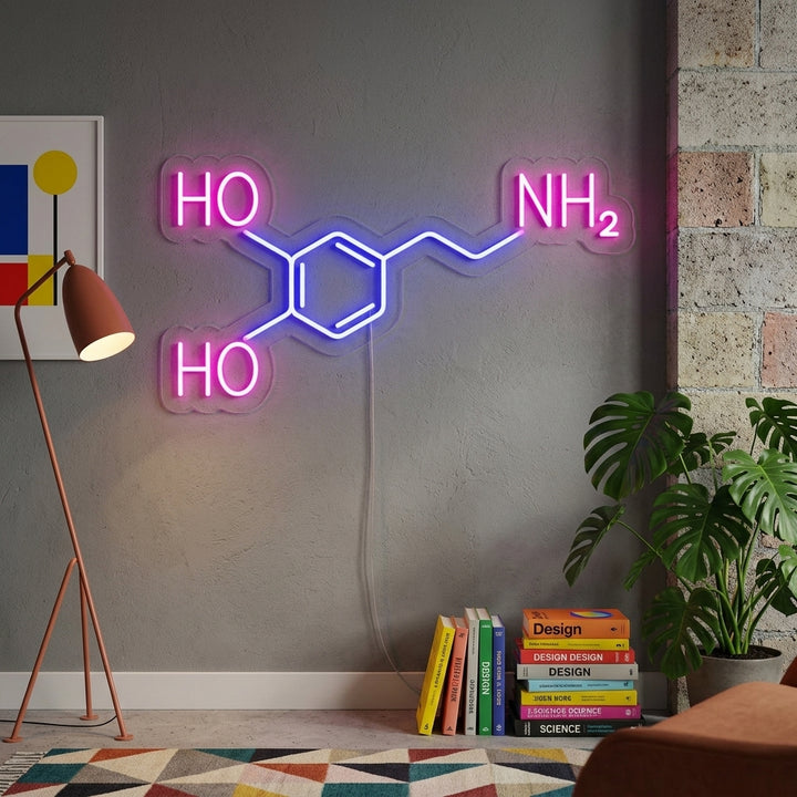 A glowing Dopamine Molecule Neon Sign hanging on a dark wall above a desk with books and a laptop, creating a stylish and intellectual atmosphere.