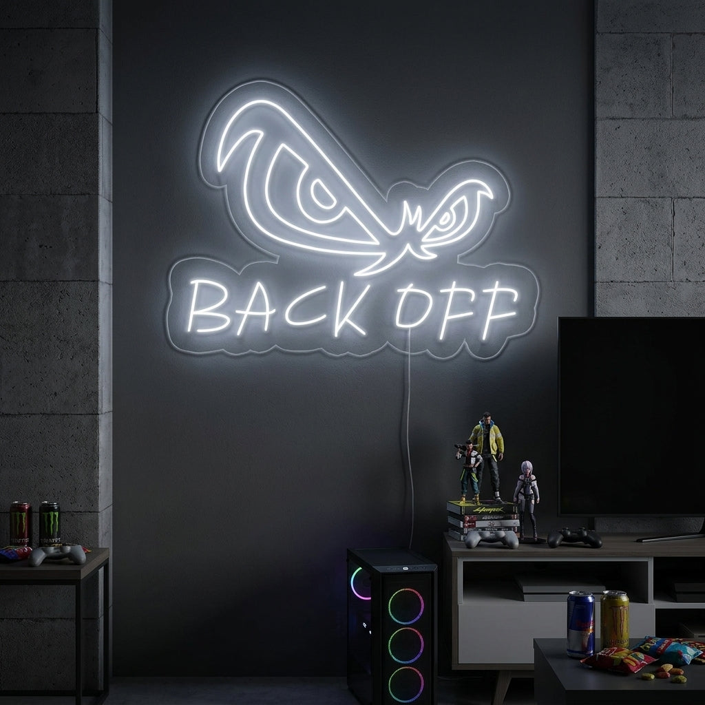 A vibrant 'Back Off Eagle Eyes' neon sign glows blue in a contemporary living room setting, mounted on a grey wall above a sleek black sofa with patterned cushions.