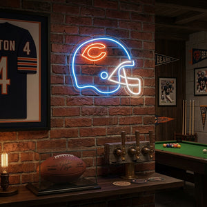 A illuminated glowing red and yellow neon sign shaped like a football helmet mounted on a stone wall in a dimly lit, cozy room with soft ambient lighting.