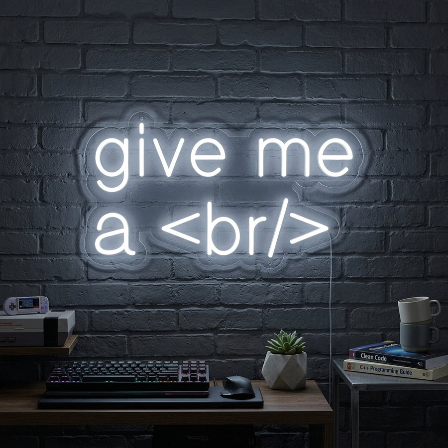 A close-up view of the illuminated 'Give Me A Break For Geeks' neon sign hanging on a textured blue wall in a modern office or tech setup.