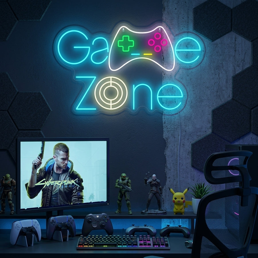 A close-up photograph of a glowing blue and green Game Zone neon sign with a game controller graphic, mounted on a dark textured wall in a gaming room.