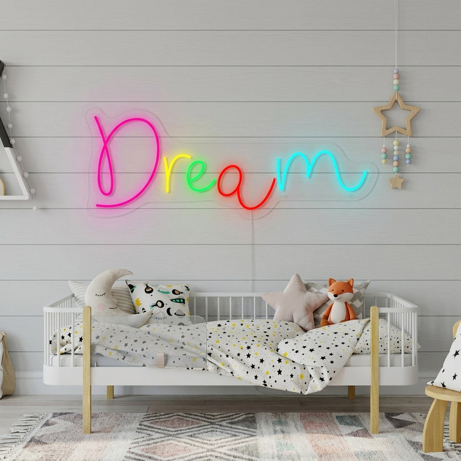 A lifestyle photo showing the glowing 'Dream' script neon sign hanging on a textured wall in a styled kid's bedroom, casting a soft glow over a made bed and decorative items.