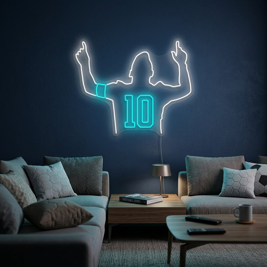 A glowing blue neon sign showing the number 10 in a modern font, hanging on a textured wall in a home office setting