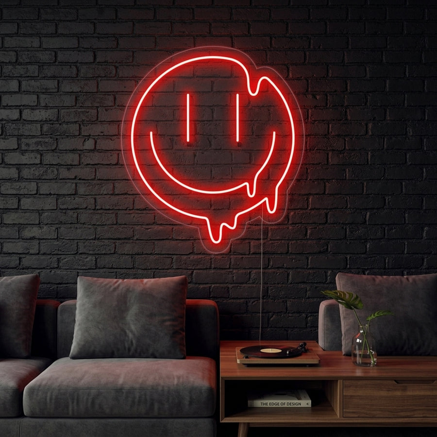 A glowing yellow Melting Smile Neon Sign with a dripping design is mounted on a textured brick wall, illuminating a cozy, edgy bedroom corner with soft light.