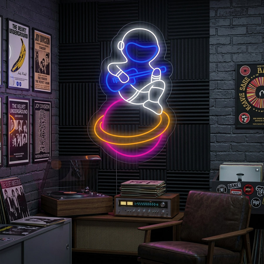 A neon sign showing a musician astronaut playing guitar while sitting on a planet, glowing blue and yellow against a modern room background.