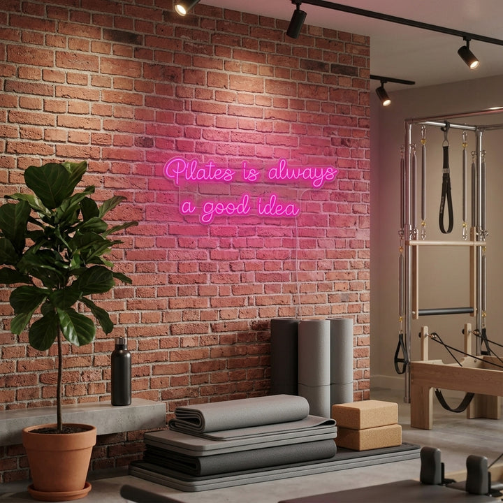 A vibrant 'Pilates is Always a Good Idea' neon sign glowing on a textured wall in a modern studio setting.