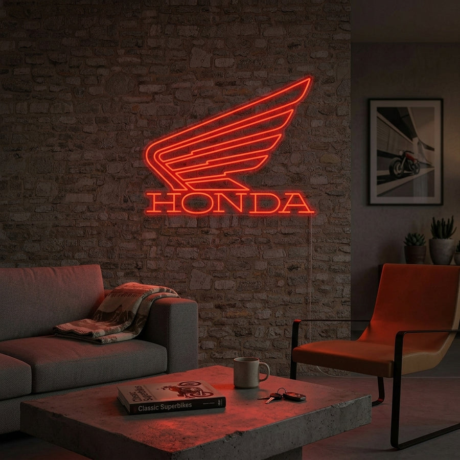 Illuminated Honda wing logo neon sign mounted on a brick wall, providing a bright glow in a garage setting.