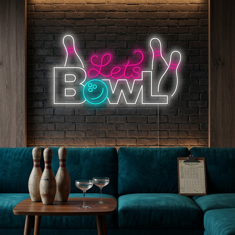 A glowing 'Let's Bowl' neon sign with a bowling pin and ball icon mounted on a brick wall above a bowling lane.