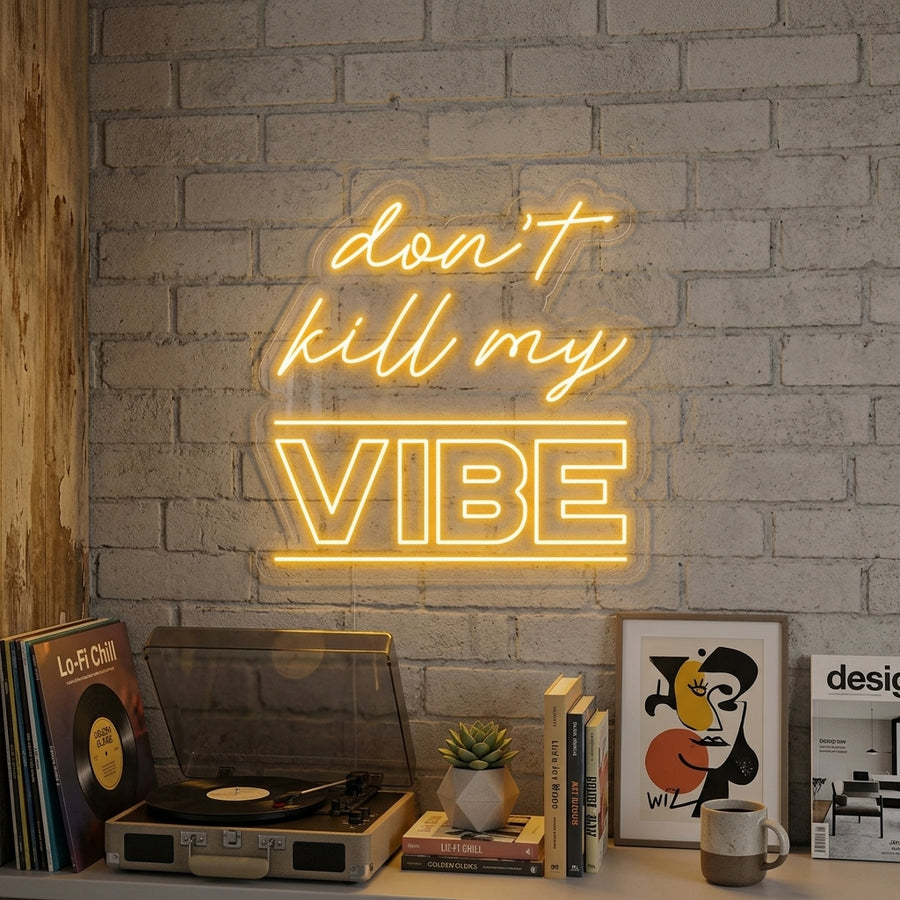 A glowing blue 'Dont Kill My Vibe' neon sign mounted on a textured brick wall above a cozy lounge chair in a modern living room setting.