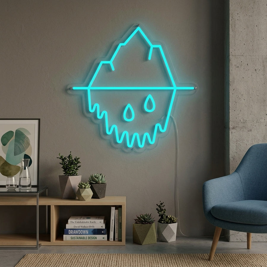 A glowing blue and white neon sign shaped like a melting iceberg, hanging above a comfortable grey armchair in a modern living room setting.