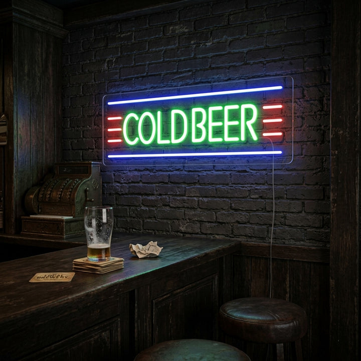 A vibrant 'Cold Beer' neon sign glowing in white and orange script on a brick wall above a cozy home bar setting.