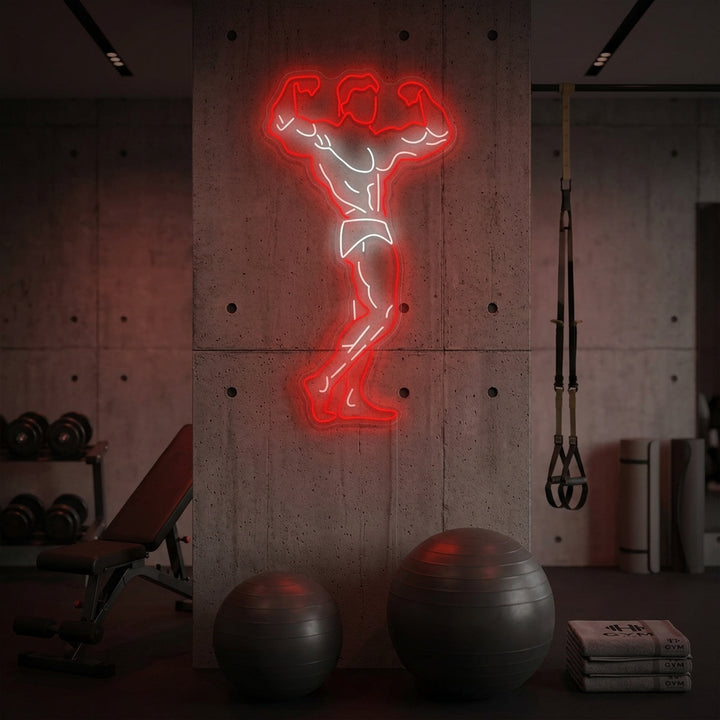 A vibrant 'Gym Hero' neon sign with an energetic glow mounted on a dark wall above workout equipment in a home gym setting.
