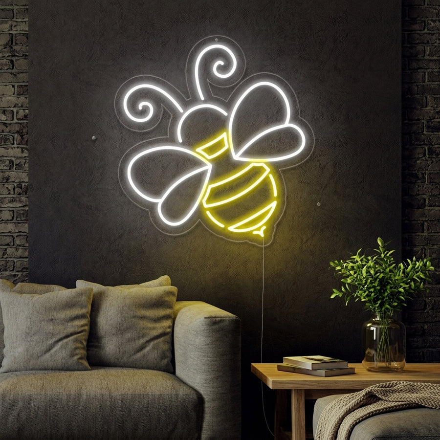 Cozy room interior with a glowing bee-shaped neon wall sign positioned above a natural wood desk and houseplant.