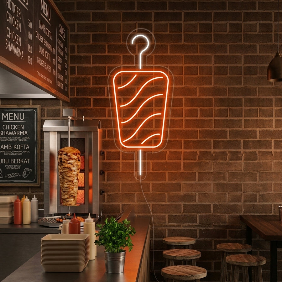 A glowing kebab neon sign displayed prominently above the service counter in a busy restaurant, casting a warm light.
