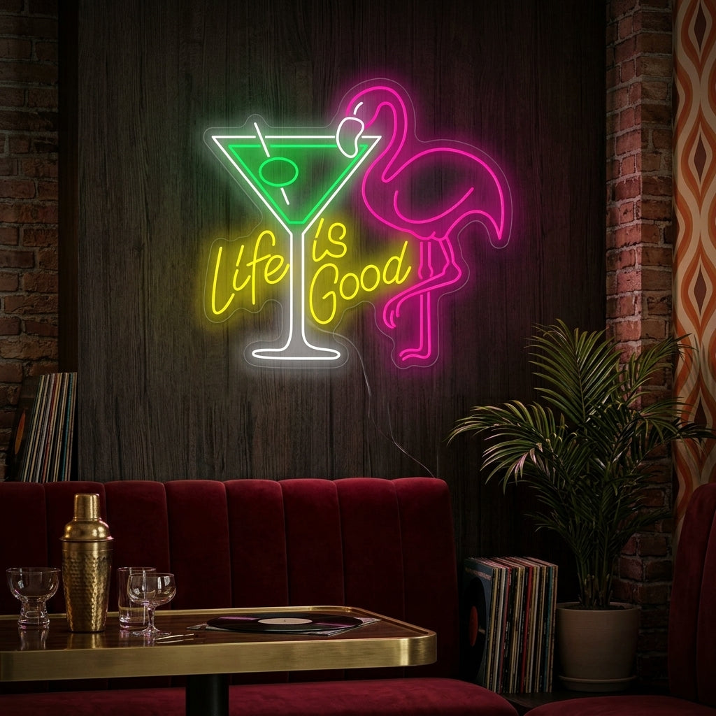 Life Is Good cocktail neon sign glowing above a home bar setup next to a plant.