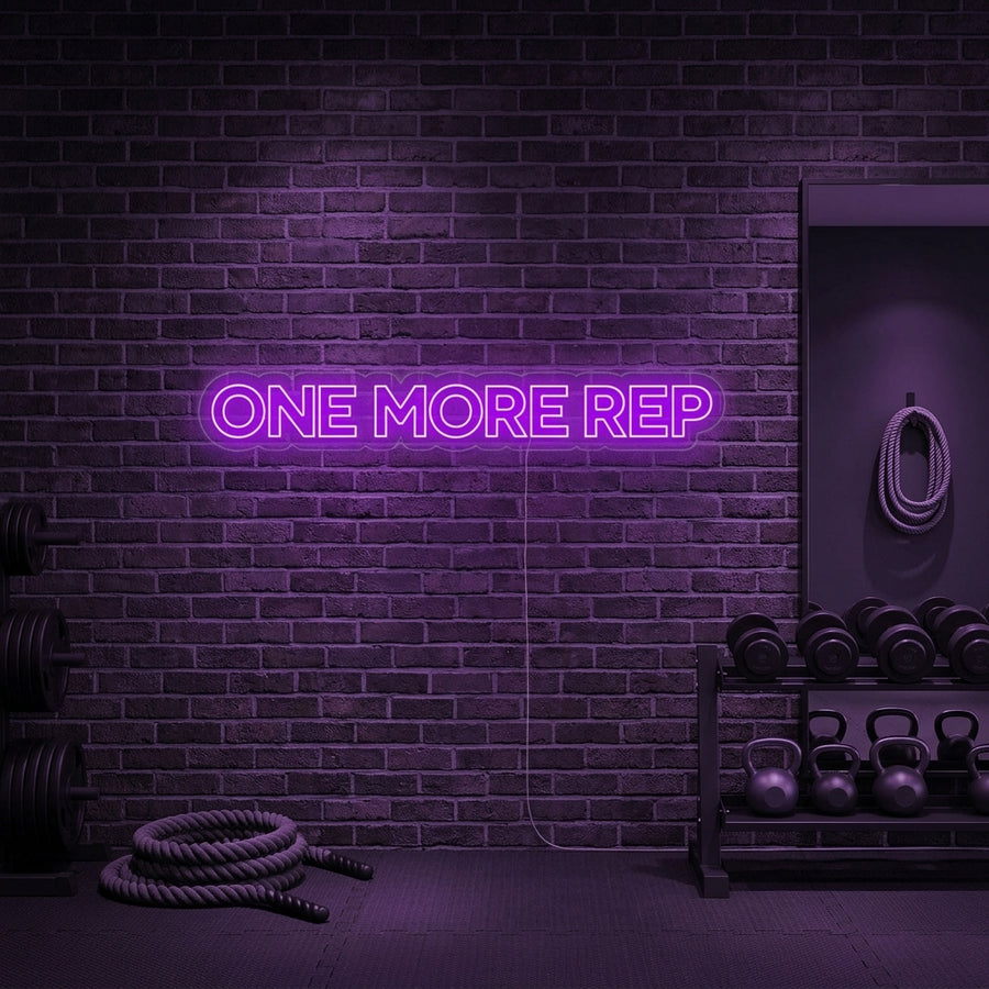 A vibrant 'One More Rep' neon sign glowing on a textured gym wall, motivating a workout.