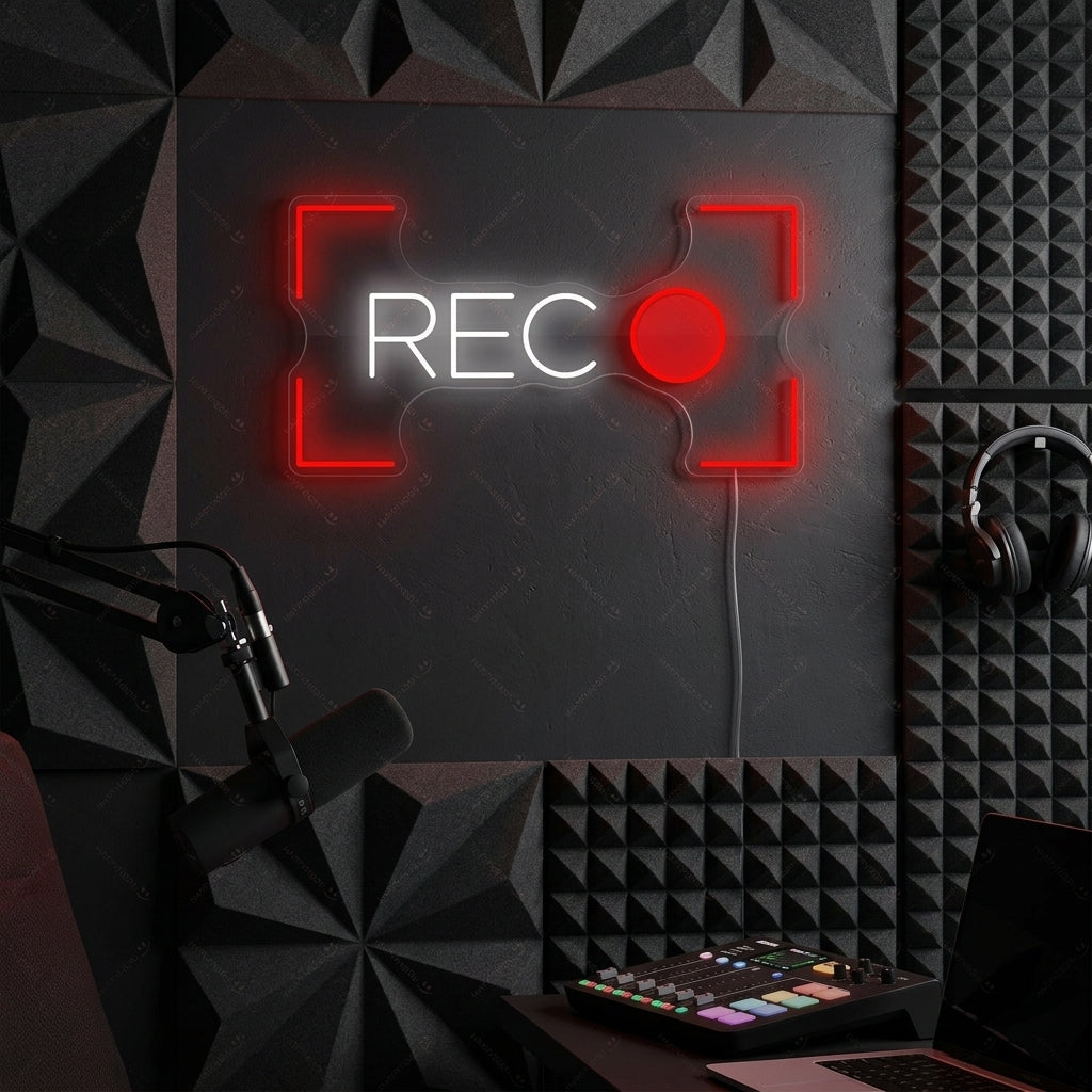 A glowing 'Recording Button' neon sign styled on a wall in a home music studio environment.