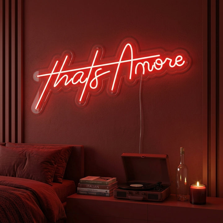 A lifestyle photo of the 'Thats Amore' neon sign glowing in warm light above a cozy bar area.